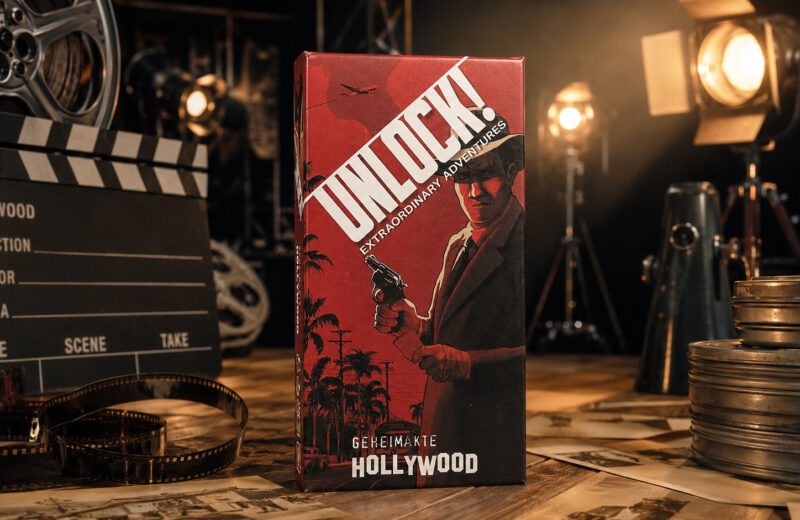Die Schachtel des Spiels „Geheimakte Hollywood“ steht in einem Filmstudio im Hollywood der 50er-Jahre.