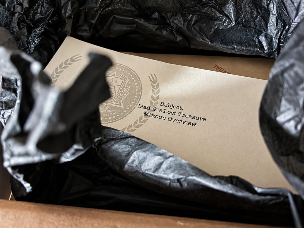 Blick in die Box von „Madoks Lost Treasure“. Mehrere geheimnisvolle Dokumente warten hier darauf, entschlüsselt zu werden.