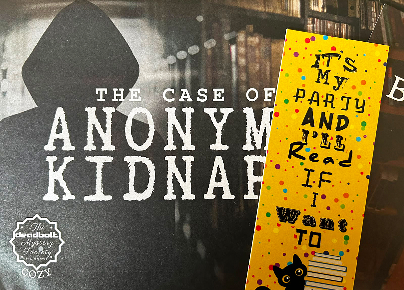 Ein Lesezeichen aus dem Spielmaterial von The Case of the Anonymous Kidnapper liegt auf einem Tisch.