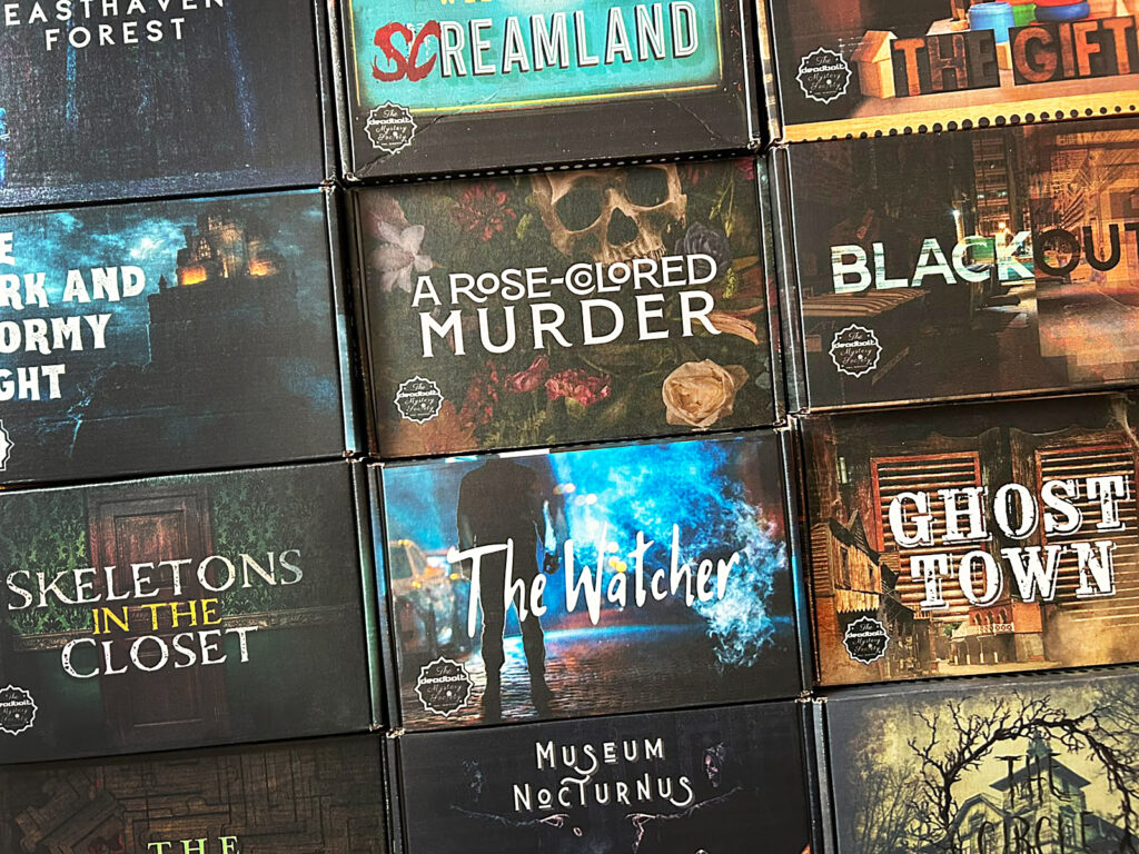 Mehrere Spiele der Deadbolt Mystery Society aus der Sammlung von Puzzle Hamstr liegen auf einem Tisch.