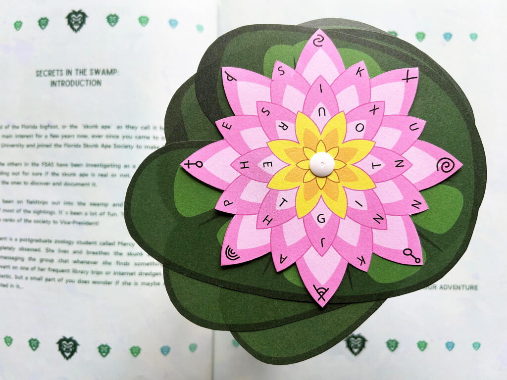 Eine Codescheibe in Form einer Seerose aus dem Buch „Secrets in the Swamp“ liegt auf dem aufgeklappten Buch.
