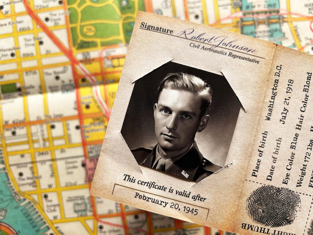 Ein Ausweis aus Zeiten des Zweiten Weltkrieges liegt auf einem Tisch, darunter ist ein Stadtplan von New York zu sehen.