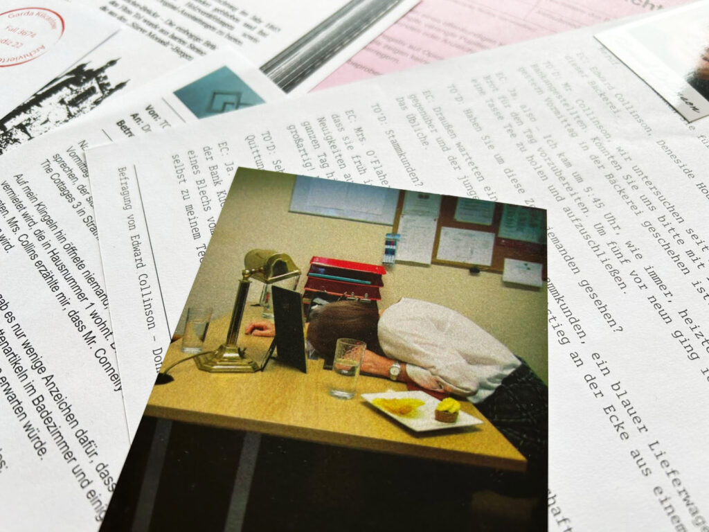 Ein Tatortfoto aus dem Spiel „Mord mit Zinsen“ liegt auf einem Tisch.