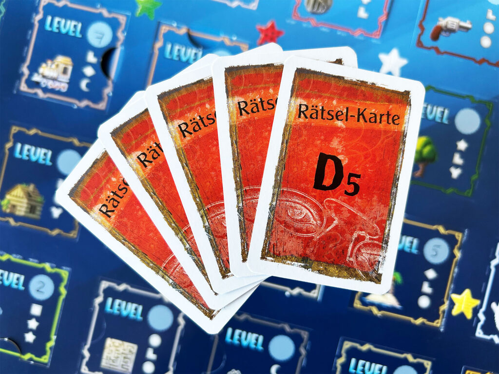 Mehrere Rätselkarten aus dem Adventskalender „Das versteckte Level“ von Kosmos liegen auf dem Kalender.