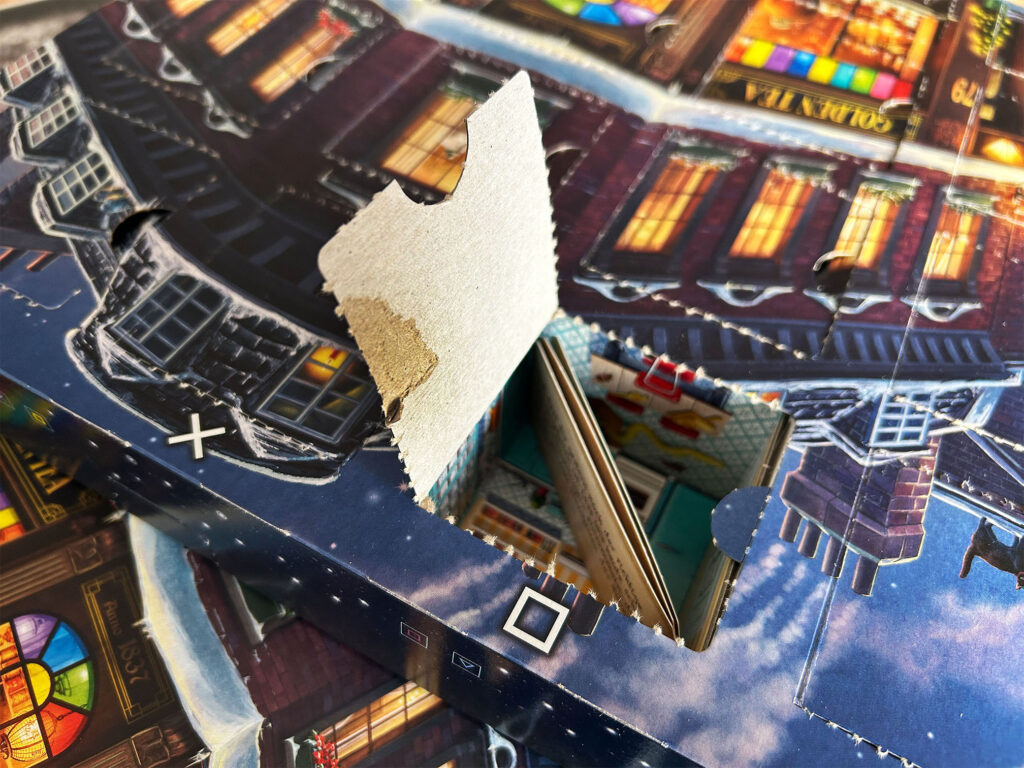 Ein eingerissenes Türchen am Adventskalender „Der kleine Teeladen“ von Ravensburger.