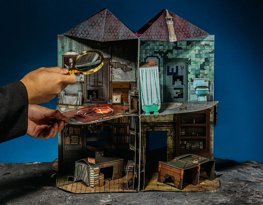 Two hands examine the “Mystery Manor” pop-up game from the Mysterious Package Company’s “Doomensions” series.